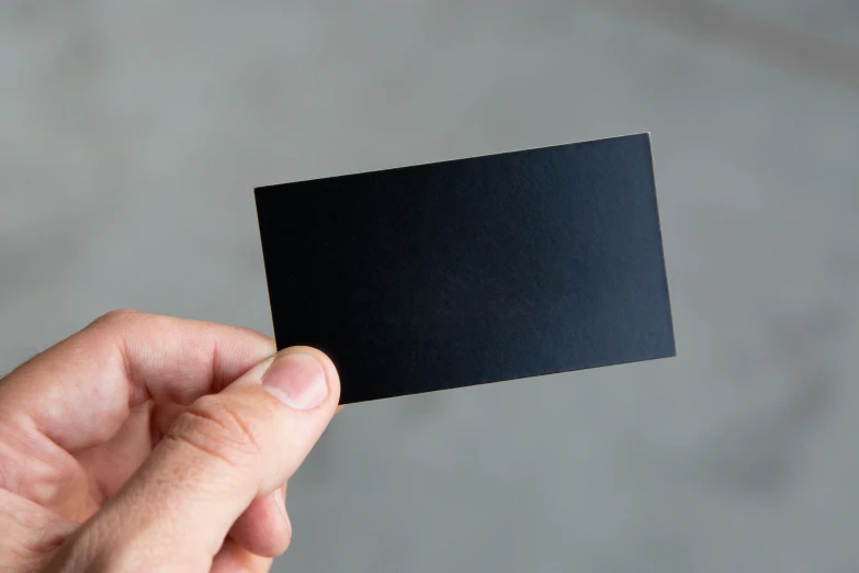 a hand holding a square black card