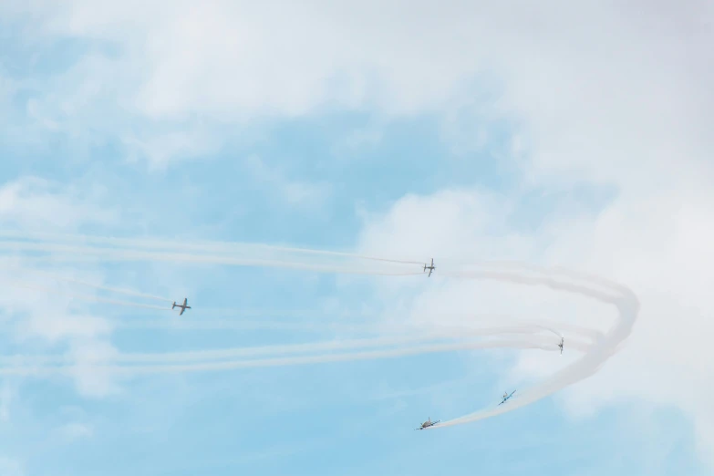 four airplanes flying in formation with smoke behind them