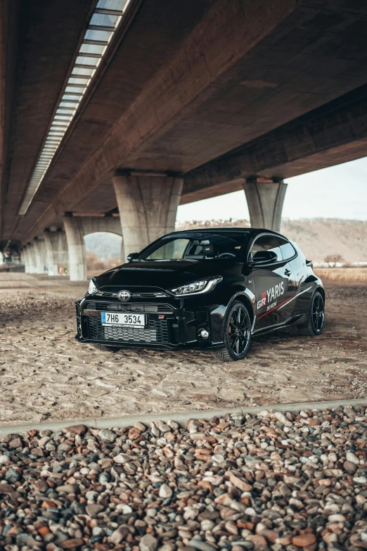 a car is parked under a bridge on rocks