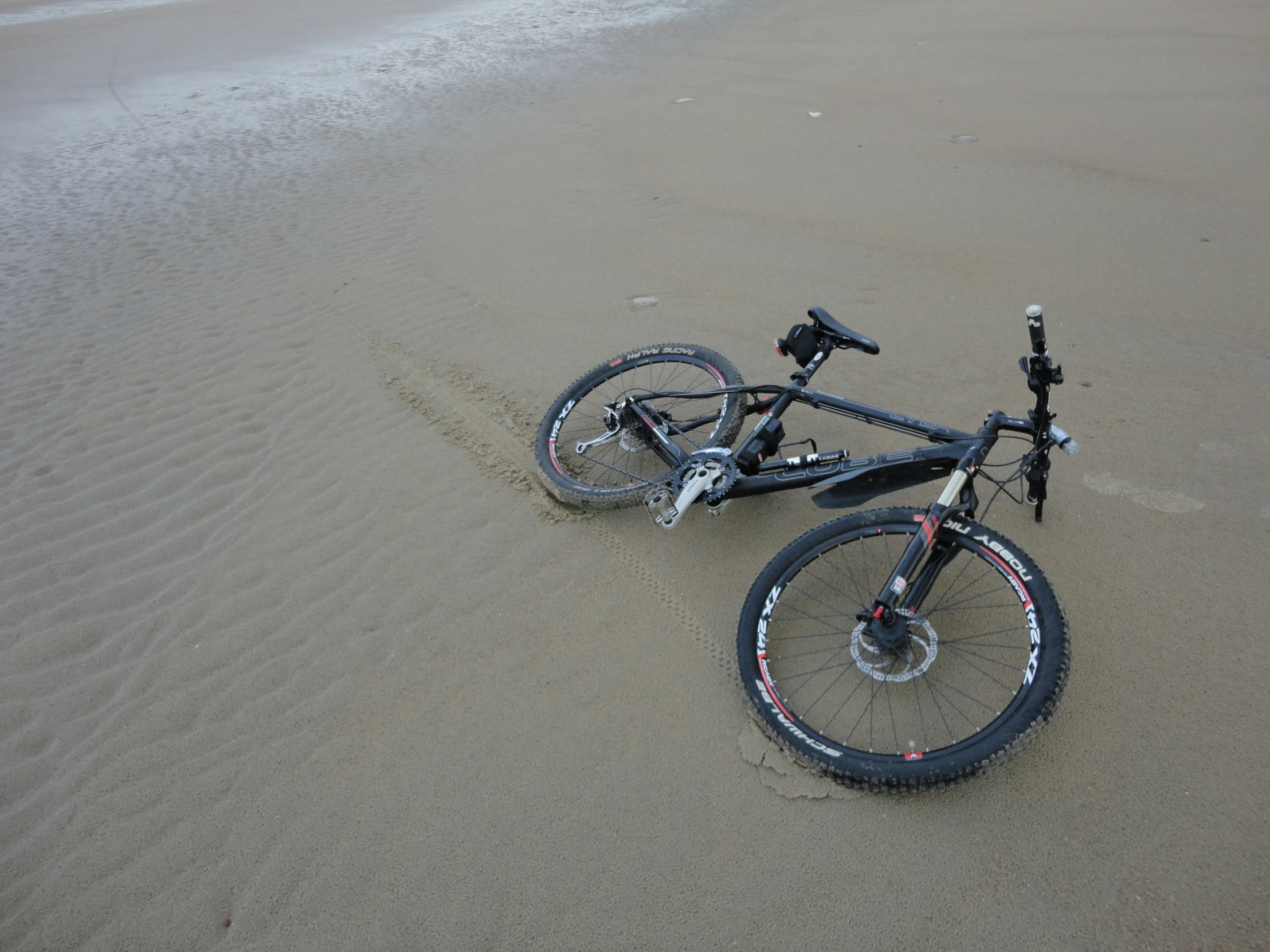 a bike laying on the sand at the beach