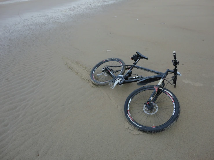 a bike laying on the sand at the beach
