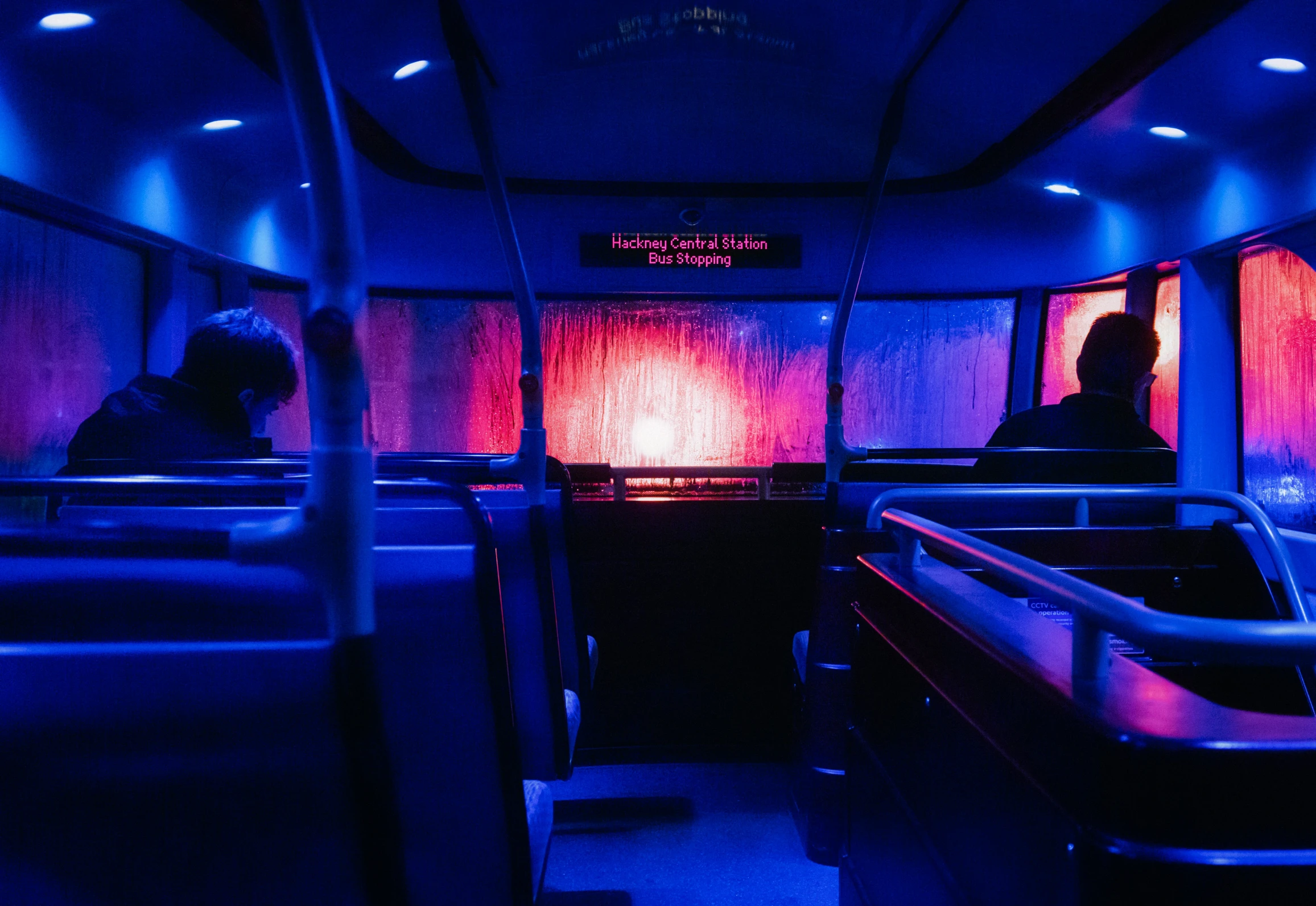 three people sit in a vehicle with purple lighting