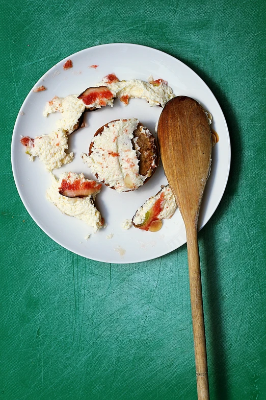 a white plate with crab meat on it and a wooden spoon