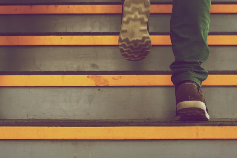 an up - close image of a person wearing blue jeans standing at the bottom of stairs