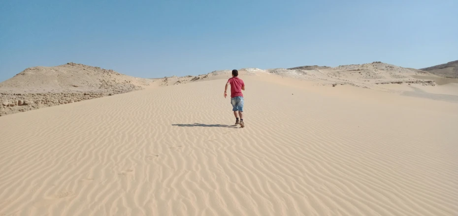 a person walking along the desert in a red shirt