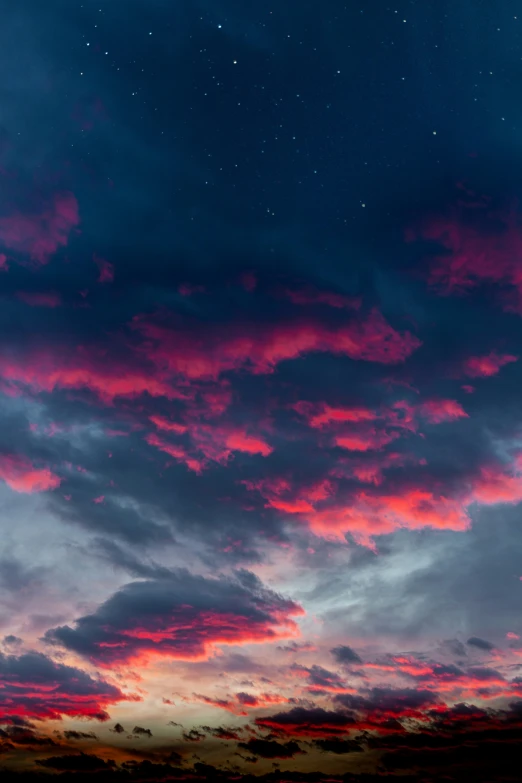 a red and blue cloudy sky with stars on the night sky