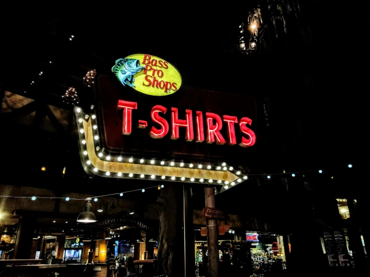 a sign reading the t - shirts on a dark city street