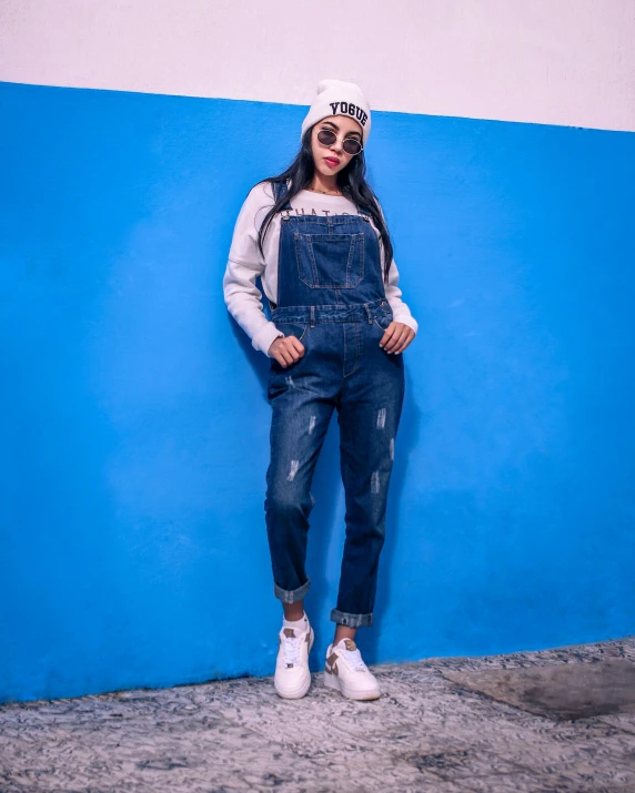 a girl is leaning against a blue wall