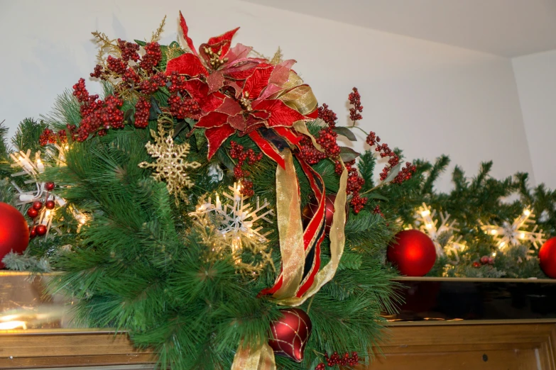 some green and red wreath hanging from a mantel