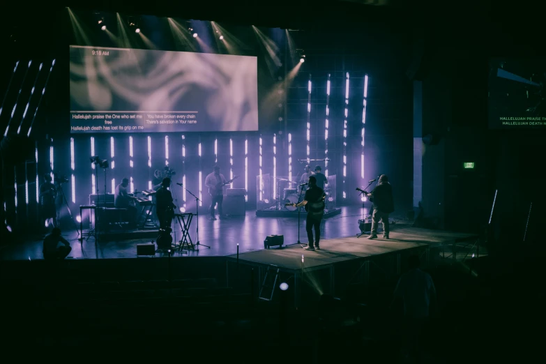 band on stage with projector lighting shining in the dark