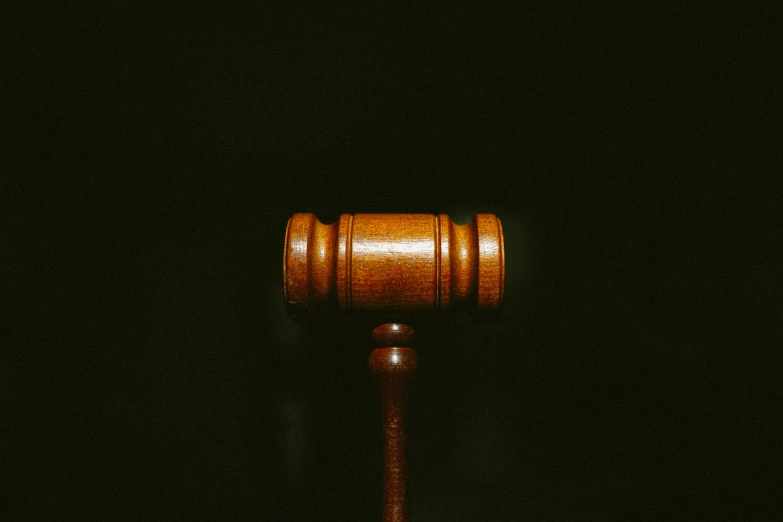 a wooden judge's hammer against a dark black background