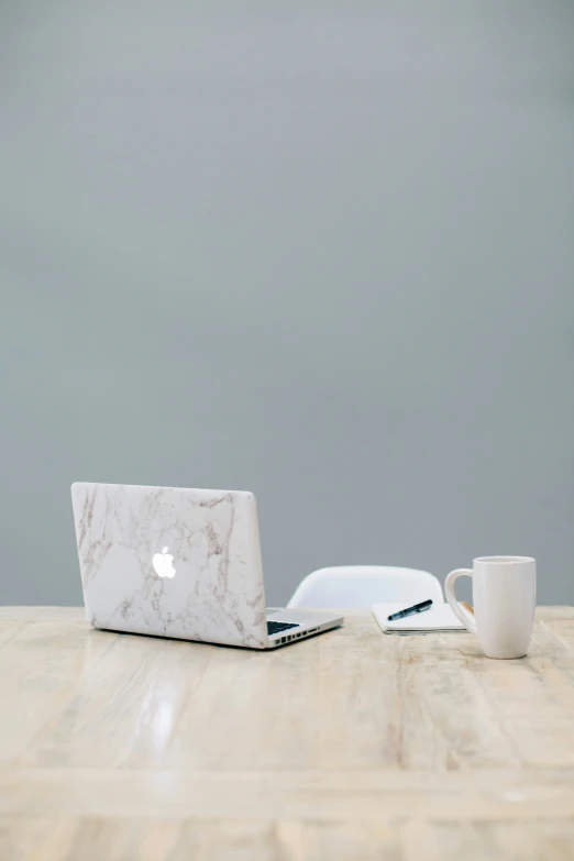 a table with a white marbled laptop and cup