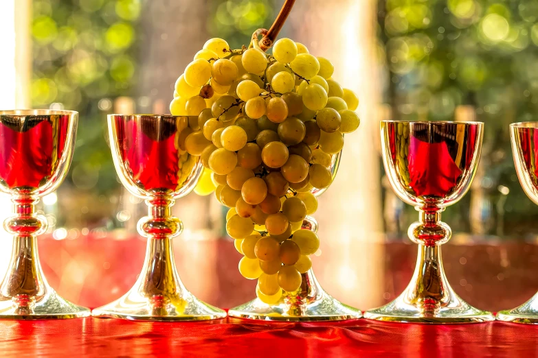 wine glasses, candles and g clusters are sitting on a red table