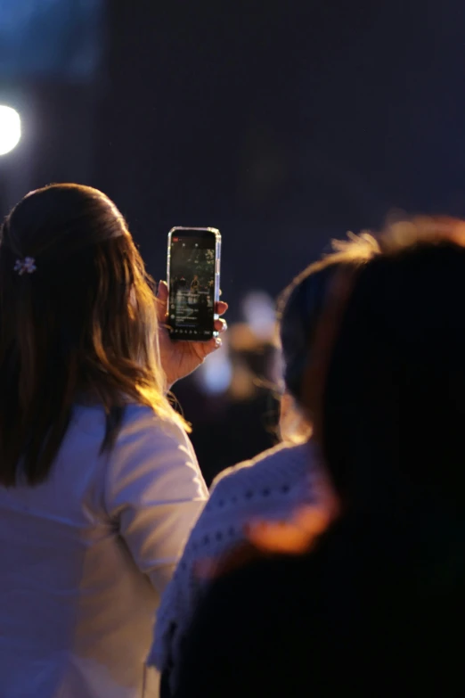 a woman is standing at night using her phone