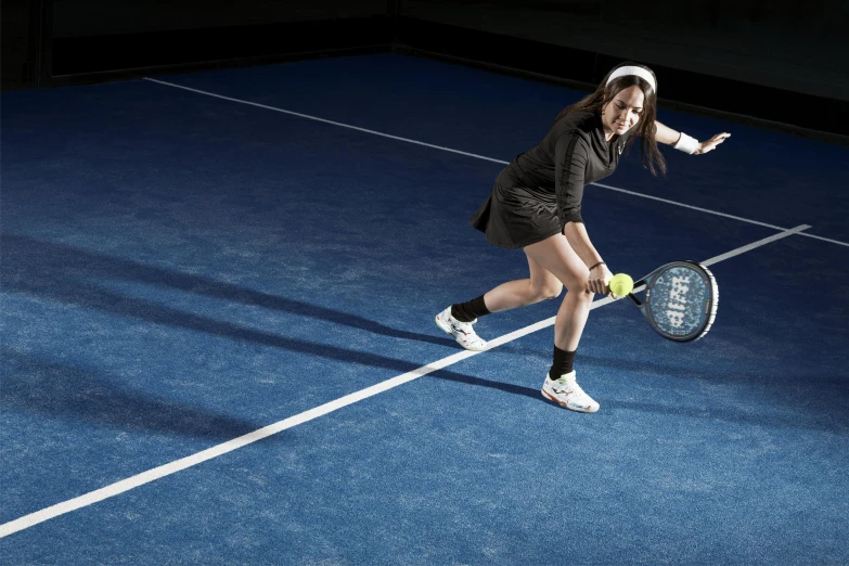 a girl is holding a tennis racket about to hit a ball