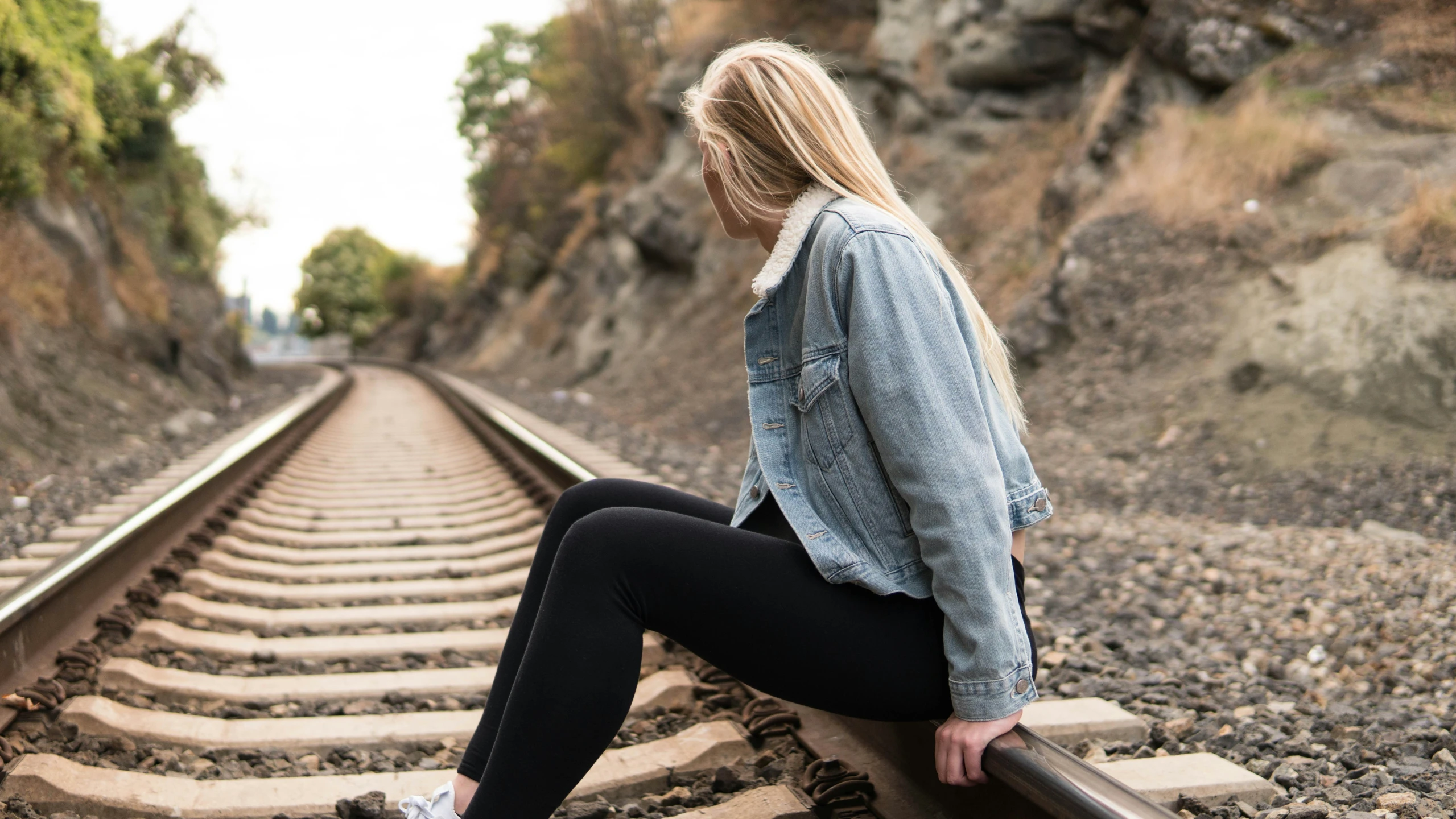 a woman sitting on a train track looking away