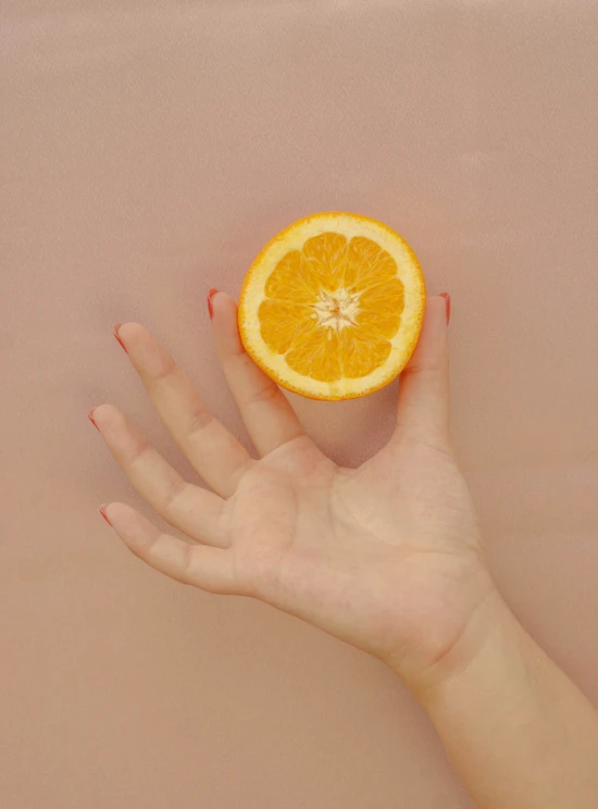 an orange is shown with its top half lifted up and held in someones hands