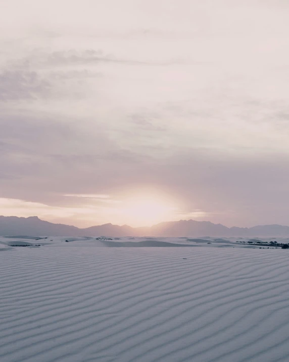 a sun shining over a mountain range with sand