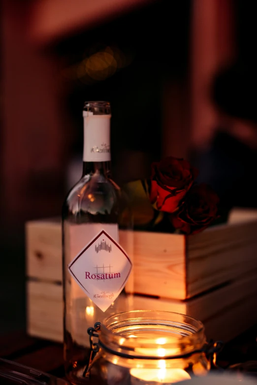 bottle with candle inside sitting on table with wooden box