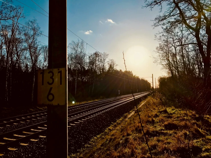 the sun rises on the horizon over a train track