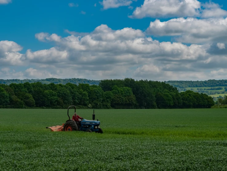 a blue tractor is driving through a large green field