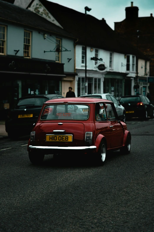 an older red car is parked in front of a shop