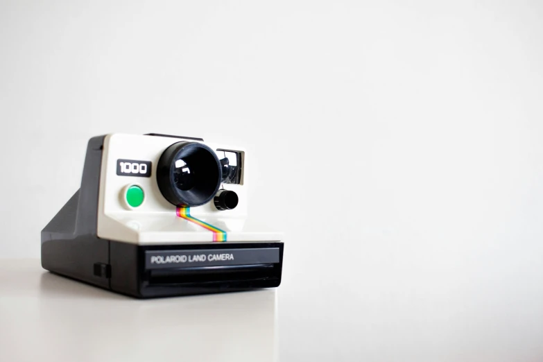 an old fashioned polaroid camera sitting on top of a white table