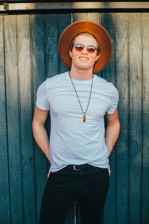 a man in a hat standing by a wall