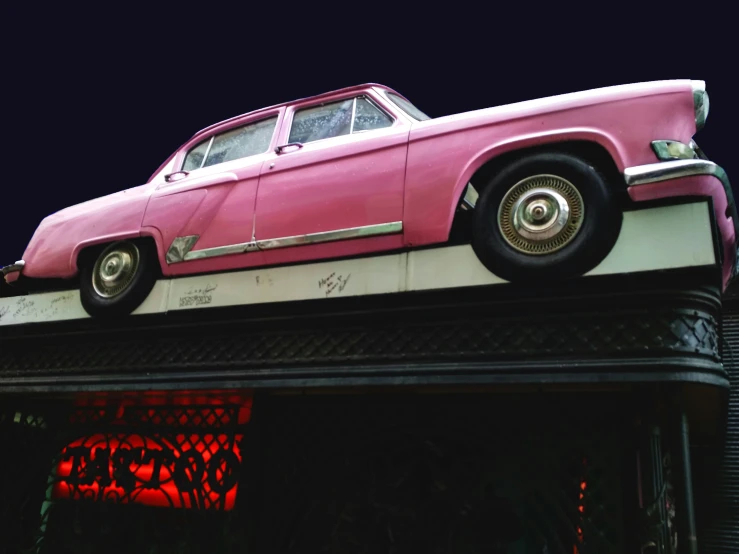 a pink car is parked on top of a red object