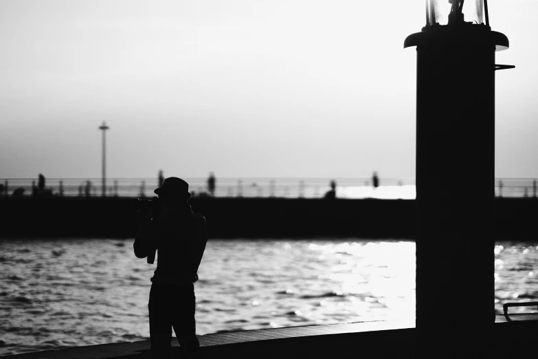 a person standing on the shore in front of the water looking at the lighthouse