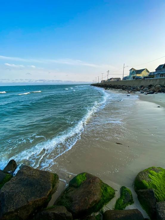 the beach with rocks and houses in the background