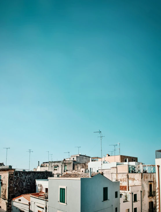 rooftops with houses and buildings in background, against blue sky