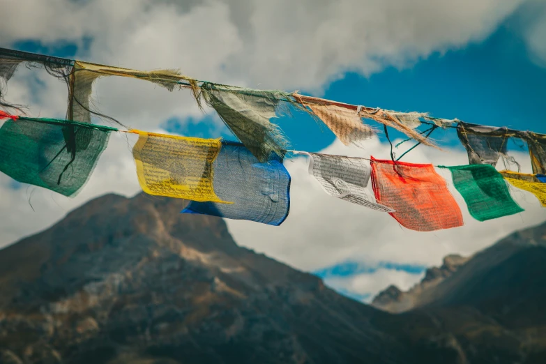 many colorful flags are hung in front of a mountain