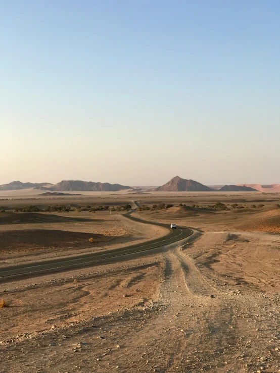 the desert has a large road with an asphalt side walk that extends into the distance