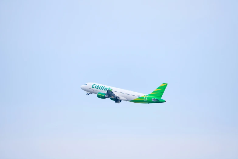 the green and white passenger plane is flying through the air