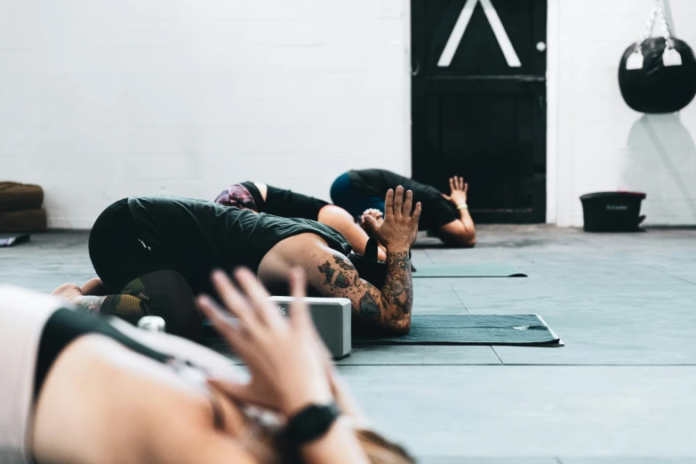 people doing yoga in a gym with their hands up in the air