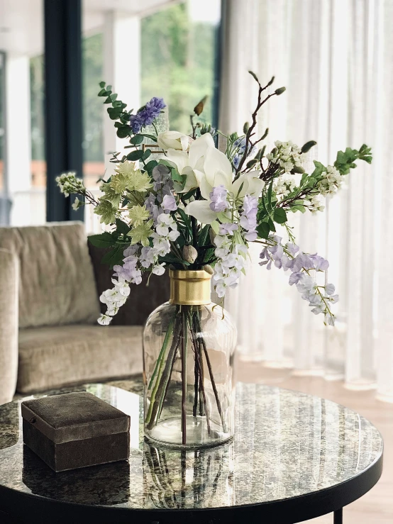 a table with a glass jar on it with flowers inside