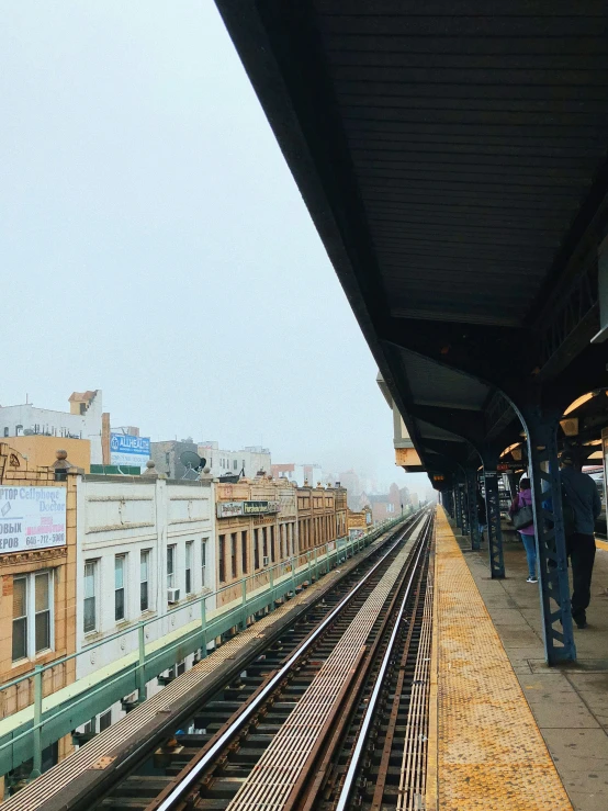 people are waiting at a station waiting for the train