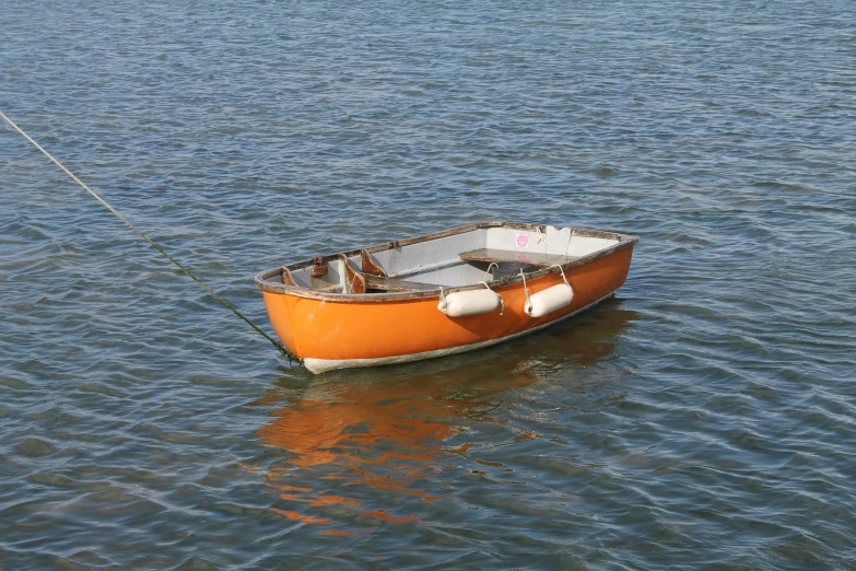 an orange boat on the water with a buoy attached to the stern