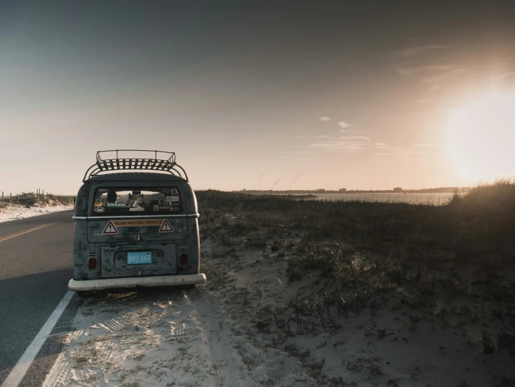 a van that has luggage on the back of it driving down a beach road