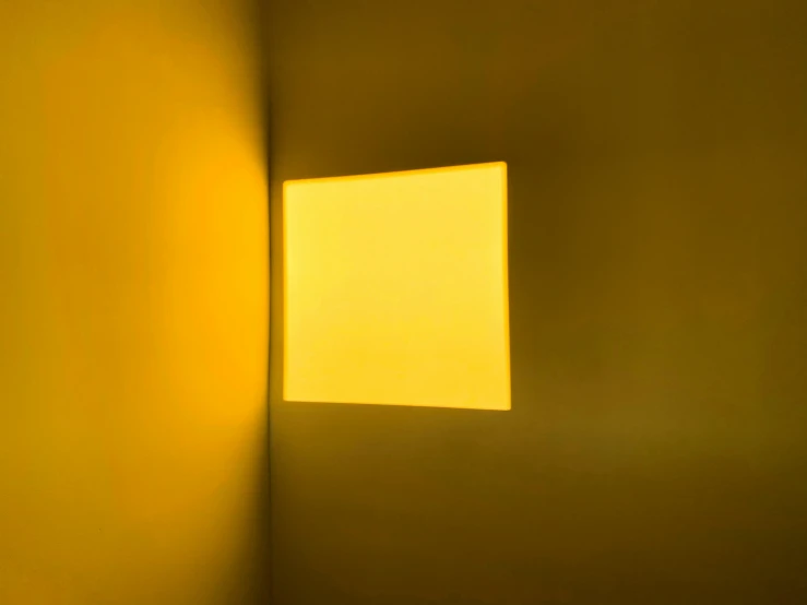a yellow square that has been framed in a white wall