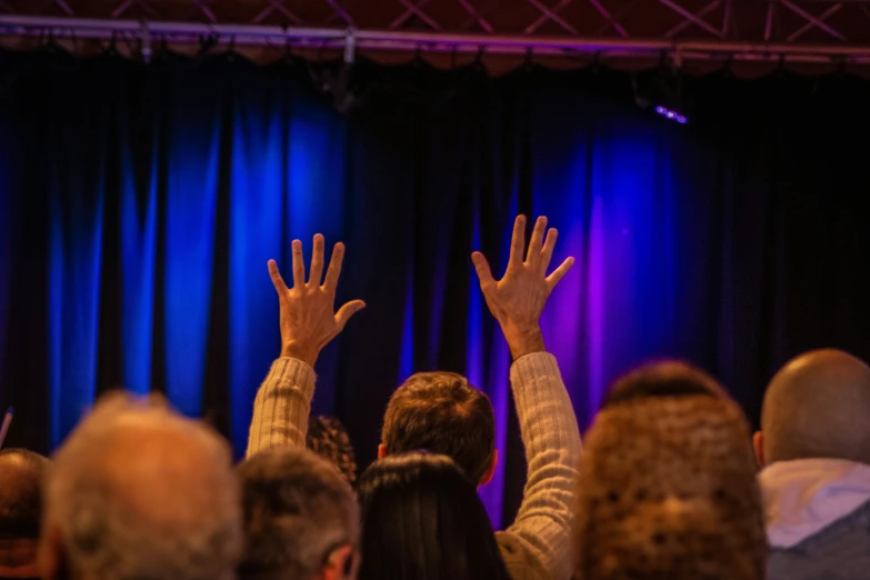 people at an event raise their hands high