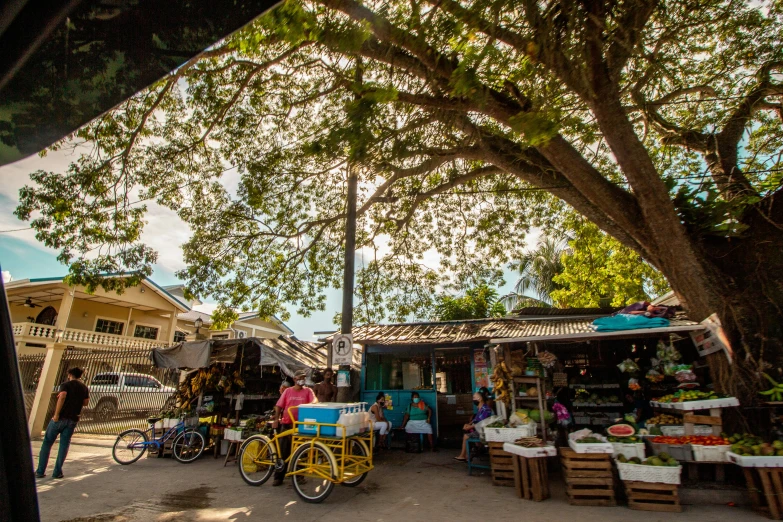 an outdoor market has several tables and stalls with fruit