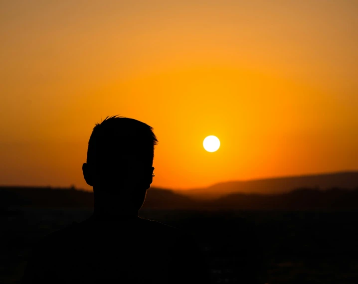 the silhouette of a man with a sunset background