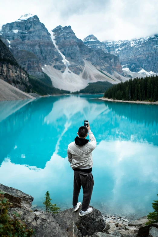 a man is taking pictures of the mountains and lake