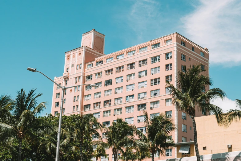 an old pink building has palm trees near it