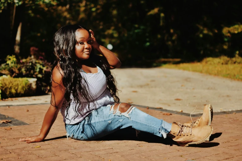 young black girl sitting on a ground holding her hair up to her ear