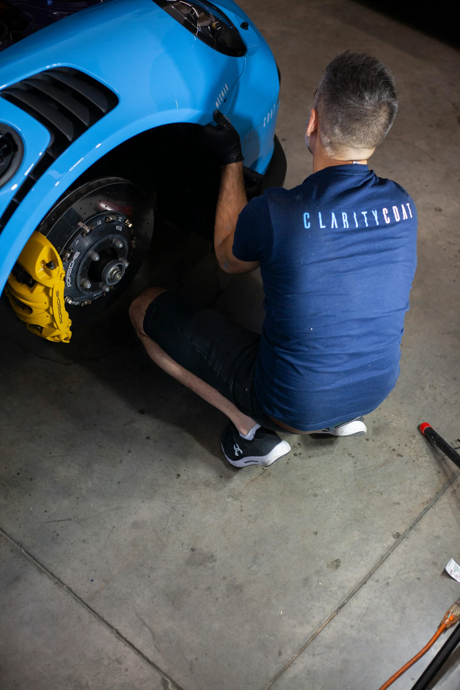 a man working on the front tire of a blue car