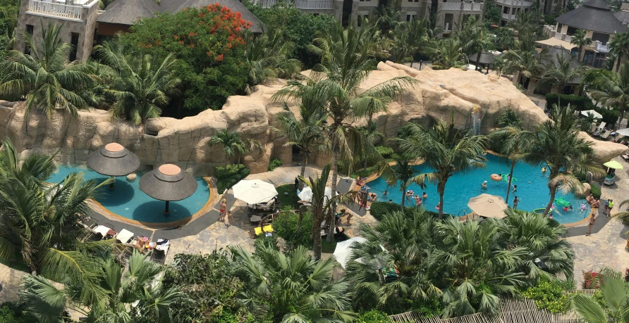 people relaxing at an outdoor swimming pool on a tropical resort