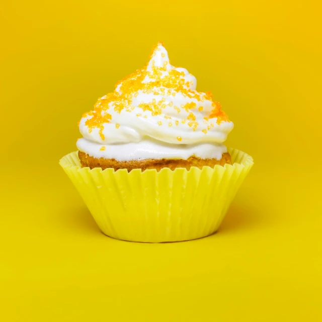 a yellow cupcake with white icing and orange sprinkles